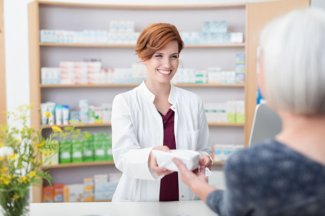 Image of female pharmacist handing over prescription to patient