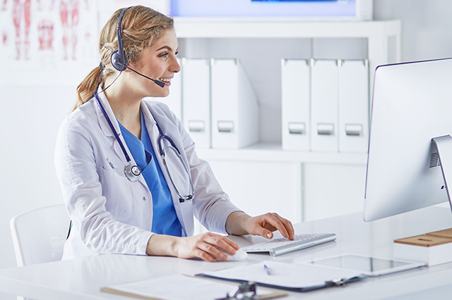 Image of female GP wearing headset talking to patient in online consultation