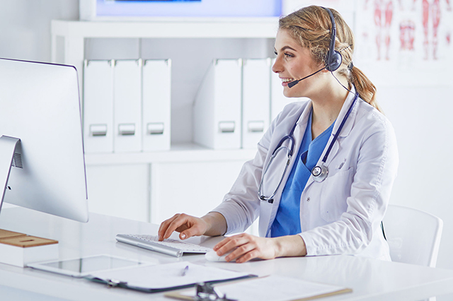 Image of female doctor wearing headset and talking to patient online
