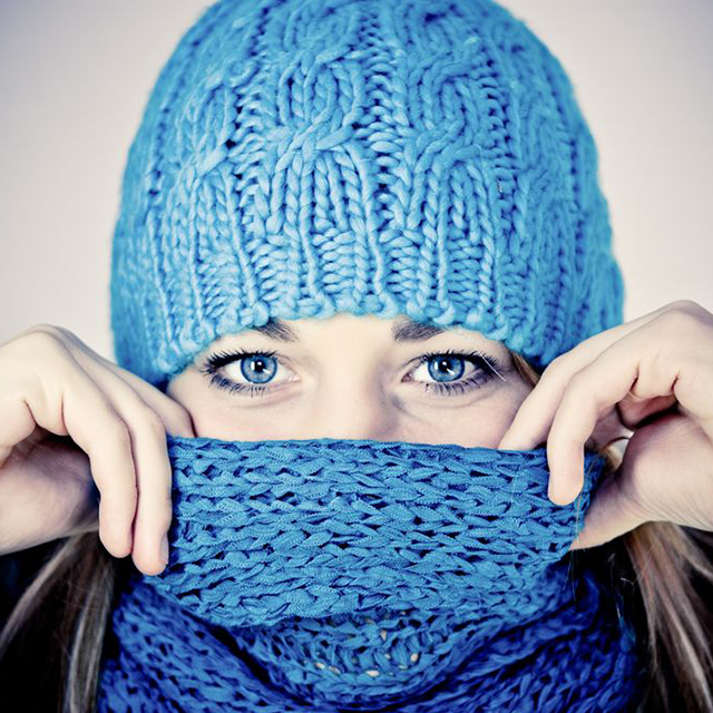 Image of woman wearing blue knitted hat and scarf